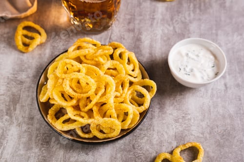 Preview: Homemade fried onion rings on a plate and sauce on the table