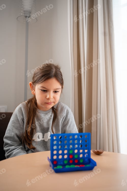 Preview: A focused child strategizing her next move in a tabletop game, embodying concentration and playful