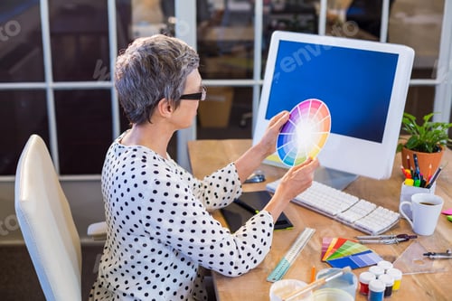 Preview: Casual businesswoman looking at colour chart in the office