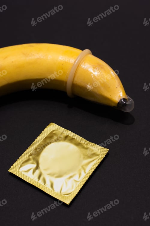 Preview: Banana with Condom on black background. Sexual Health and Education Concept