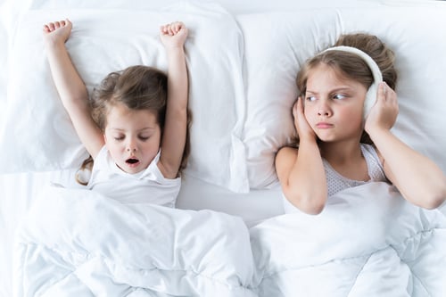 Preview: Little girls sleep in bed. One is snoring hard,sister is plugging ears with fur headphones.Early mor