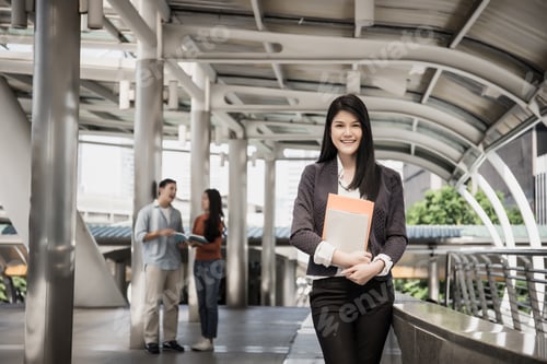 Preview: Young business woman holding reports and looking at camera.