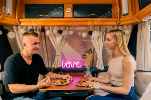 Preview: Couple in love on a date in a mobile home sitting at the table and having dinner in romantic setting