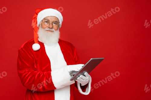 Preview: Santa Claus working on tablet copy space isolated on red background. Happy New Year 2025