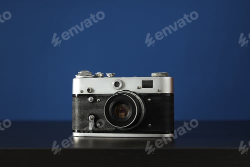 Preview: Vintage camera on wooden table on blue background, close up