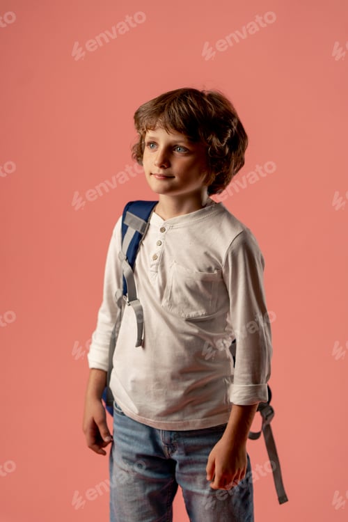 Preview: in a photo studio on a pink background stands a smiling boy of ten years old, a schoolboy in a white