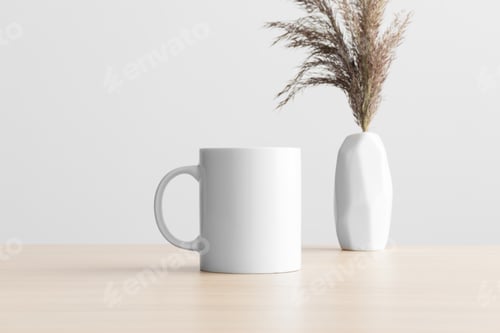 Preview: White mug mockup with a dry flower decoration on the wooden table.