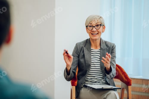 Preview: Senior woman psychiatrist talking with her patients during therapy session