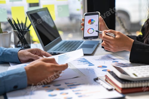 Preview: Two business people sit down to analyze financial data from earnings graphs showing the company's ea