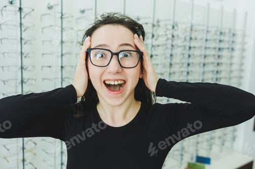 Preview: A young woman chooses glasses in an optical store. Stand with glasses.
