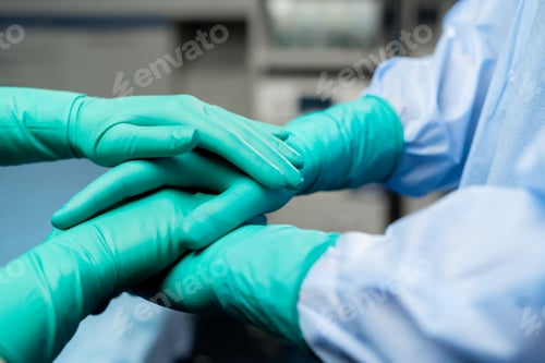 Preview: close-up of clasped hands of doctors wearing green gloves together before surgery