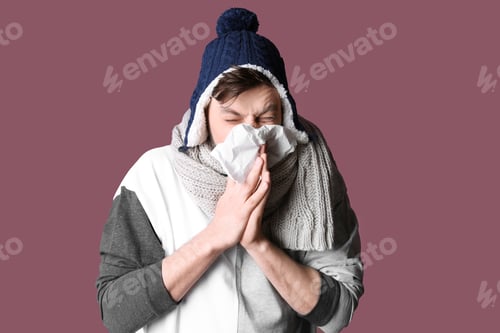 Preview: Man in warm clothes suffering from cold on color background