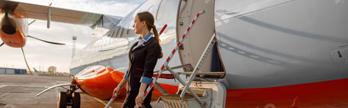 Preview: Woman flight attendant standing on airplane stairs at airport