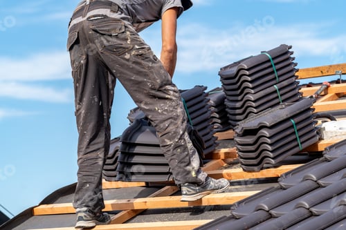 Preview: building a roof from ceramic tiles on a new family house, a craftsman on the construction site
