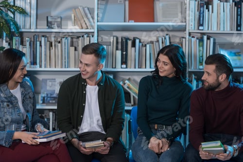 Preview: four happy multicultural friends with books in library