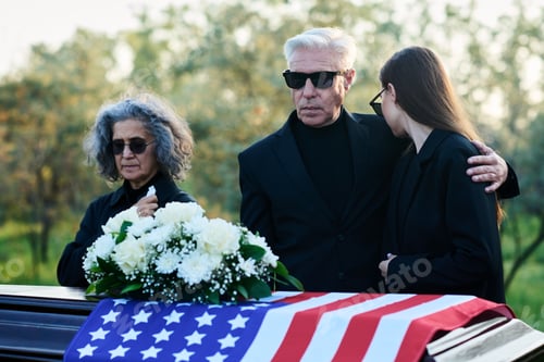 Preview: Mature man in mourning attire embracing his grieving daughter
