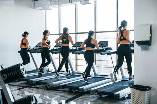 Preview: Running on a treadmill. Group of young sportive people have crossfit day indoors in gym
