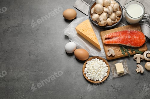Preview: Fresh products rich in vitamin D on grey table, flat lay. Space for text