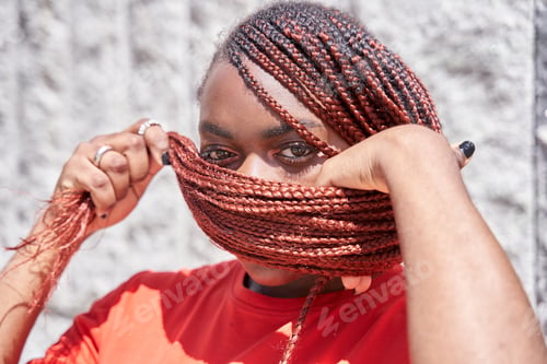 Preview: African American woman covering her face with red braided dreadlocks