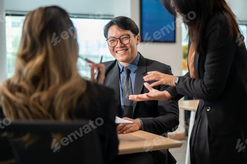Preview: Back view of businesswoman and smiling man listening to coworker talking at wooden table in office.