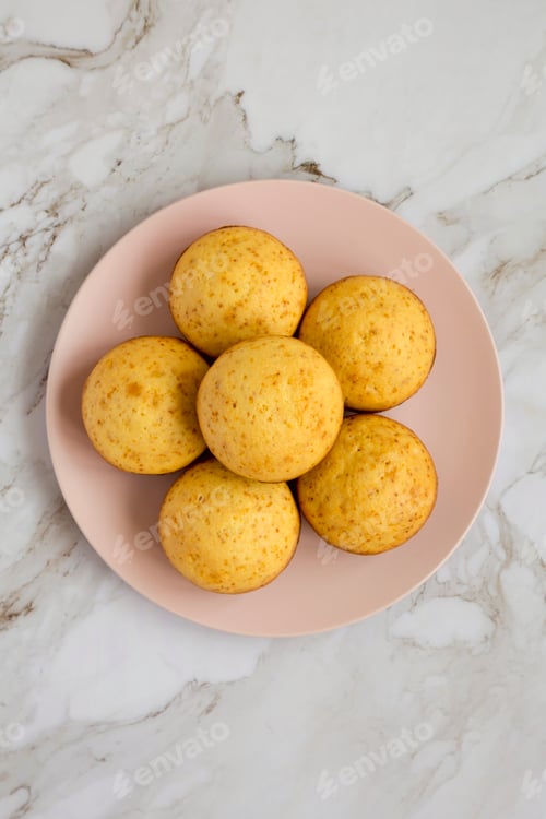 Preview: Homemade Cornbread Muffins on a pink plate, view from above. Flat lay, overhead, top view.