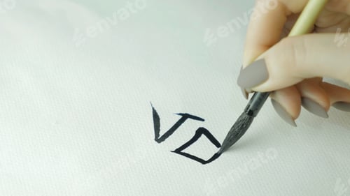 Preview: Woman's hands writing Chinese hieroglyph. Female hand holding a writing brush calligraphy Chinese