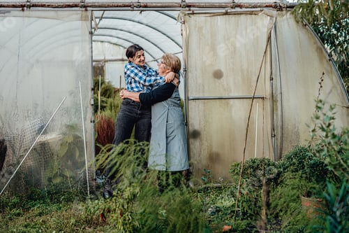 Preview: Grandmother and granddaughter in the greenhouse working day. National Grandparents Day concept.