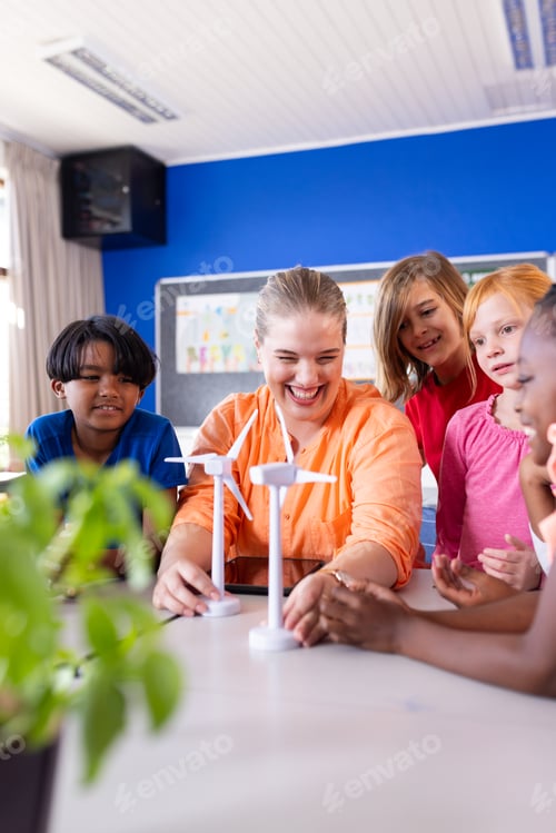 Preview: In school, female teacher and diverse students experimenting with wind turbine models in classroom