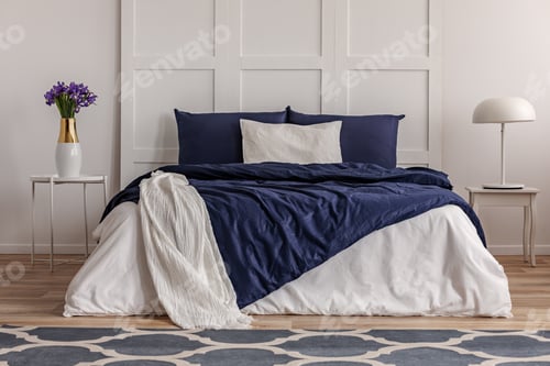 Preview: Purple flowers in white vase on elegant nightstand in fashionable bedroom interior