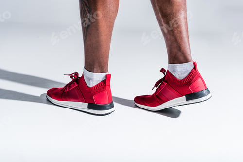 Preview: cropped shot of african american man in sports shoes on grey