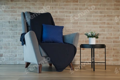 Preview: Grey armchair with table in living room interior at brick wall