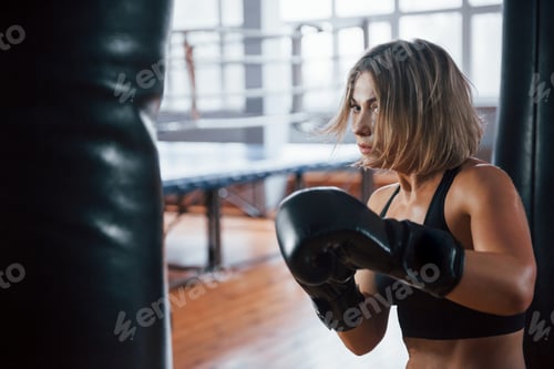 Preview: Sweat on the skin. Female boxer is punching the bag. Blonde have exercise in the gym