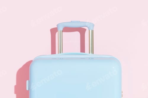 Preview: Blue suitcase on a pastel pink background with long deep shadows. Travel concept
