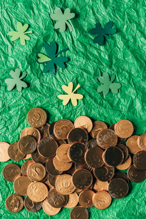 Preview: top view of golden coins and paper shamrock on green surface, st patricks day concept