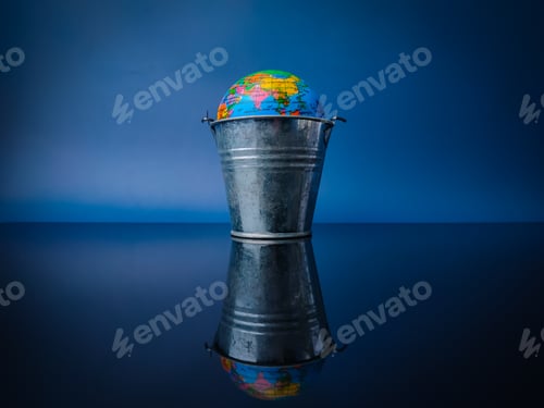 Preview: Earth globe in a steel bucket with reflection on a black acrylic board