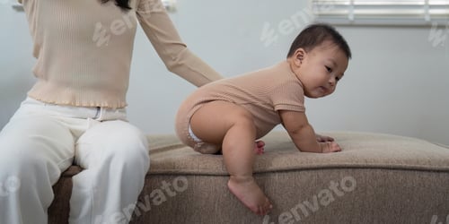 Preview: Supportive parent encouraging baby to crawl from the sofa in a stylish living room