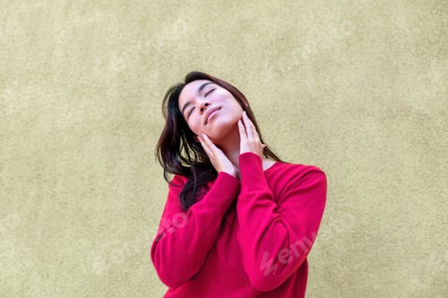 Preview: Young woman resting hands on face, eyes closed, experiencing serene moment