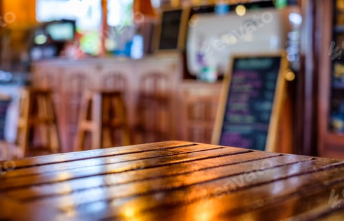 Preview: Glossy wooden table top on blurred counter bar glowing in restaurant