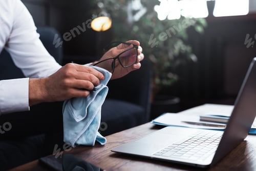 Preview: Man is cleaning his eyeglasses with a fabric cloth