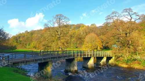 Preview: Rustic autumn scene of a stone bridge arching over the Wharfe River.