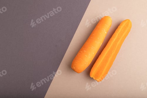 Preview: Orange Carrot on beige and gray pastel paper, Top view, copy space