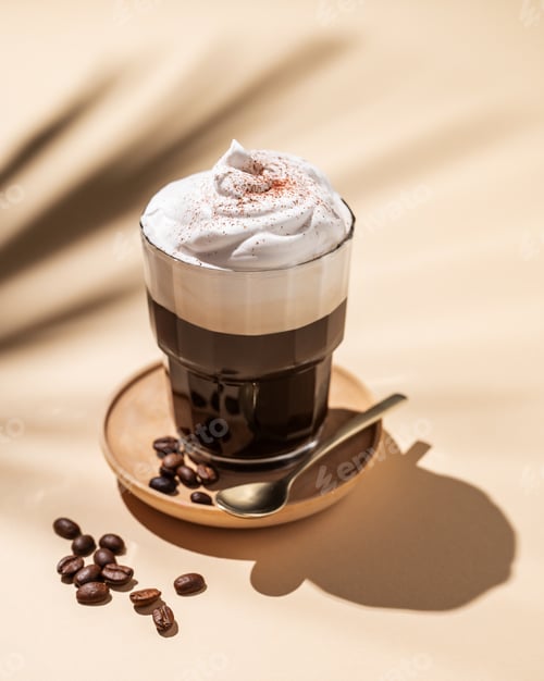 Preview: Iced coffee in a glass with foam on a yellow background with coffee beans and palm leaf shadows.