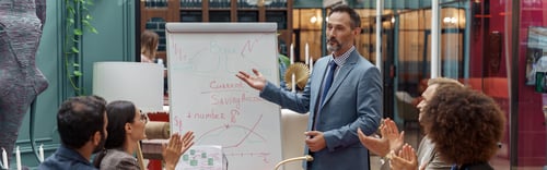 Preview: Mature business coach or speaker make flip chart presentation to diverse businesspeople at meeting