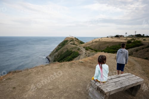 Preview: Little boy and girl looking at the sea from the top of a mountain.