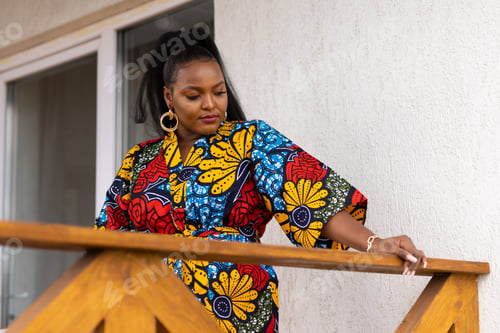 Preview: African american woman relaxing and enjoying sun while standing at terrace or balcony at sunlight at