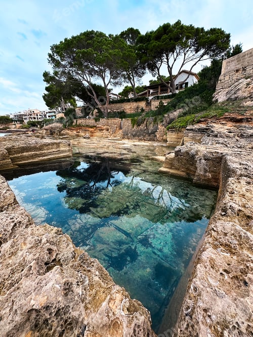 Preview: Reflection Of Tropical Trees In Water Of Blue Lagoon In Rocky Mountain On Blue Cloudy Sky Background