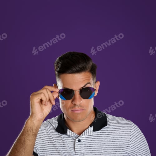 Preview: Handsome man wearing sunglasses on purple background