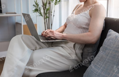 Preview: Person working remotely using laptop on modern sofa