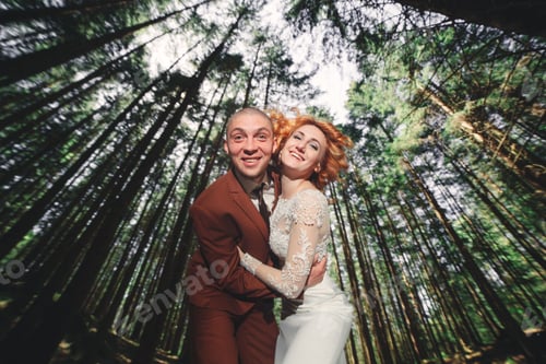 Preview: Happy stylish couple newlyweds in the green forest on summer day. bride in long white dress