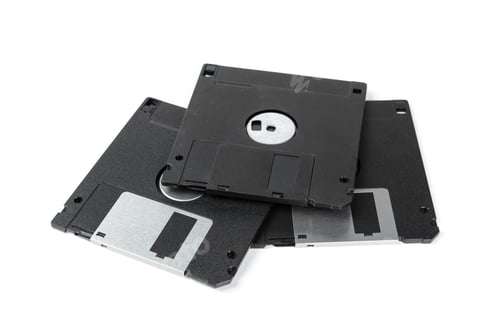 Preview: Old computer disks stacked on top of each other on a plain surface